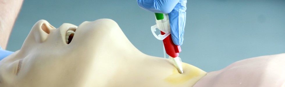 Ein Luftröhrenschnitt wird an einer Puppe mit Koniotomiebesteck durchgeführt