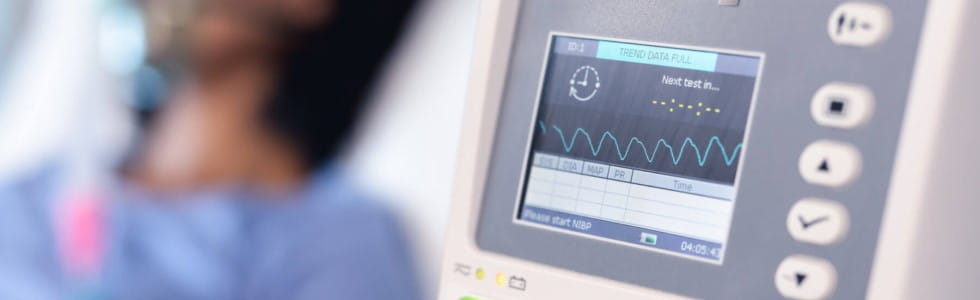 Ein Patient liegt in einem Krankenhausbett ¬– ein Patientenmonitor überwacht seine Vitalwerte
