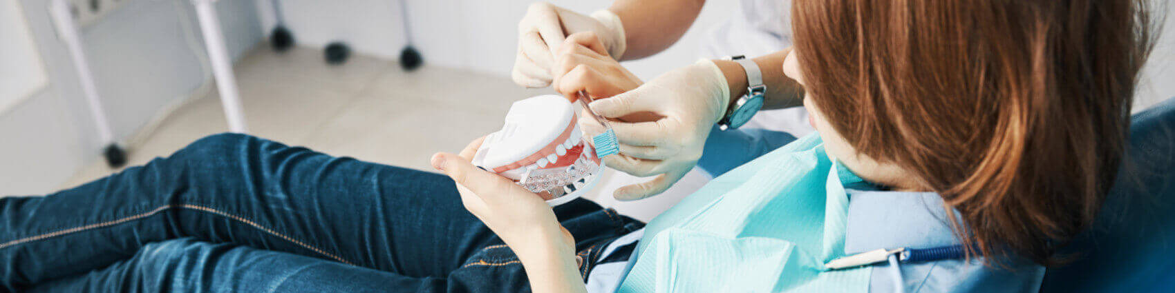 Ein Arzt erklärt einem Jungen das richtige Zähne putzen mit medizinischen Mundpflegeprodukten