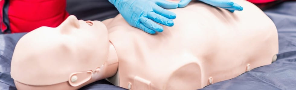 Eine Person übt den Notfall mithilfe einer CPR Puppe