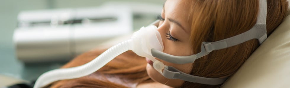 Eine junge Frau nutzt eine Maske für die CPAP-Therapie