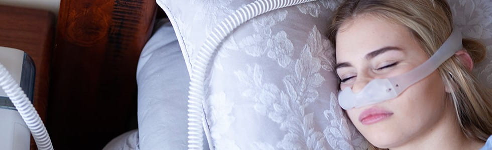 Das passende CPAP-Zubehör macht die Therapie noch angenehmer für Patienten Frau schläft während der Therapie und nutzt dabei CPAP-Zubehör