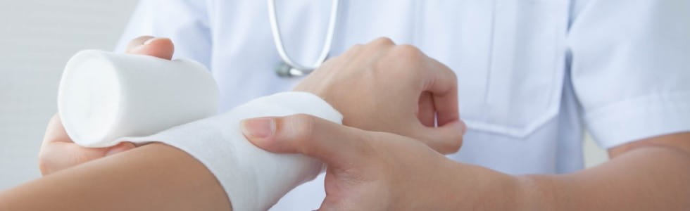 Arzt verbindet den Arm eines Patienten mit Verbandsmaterial