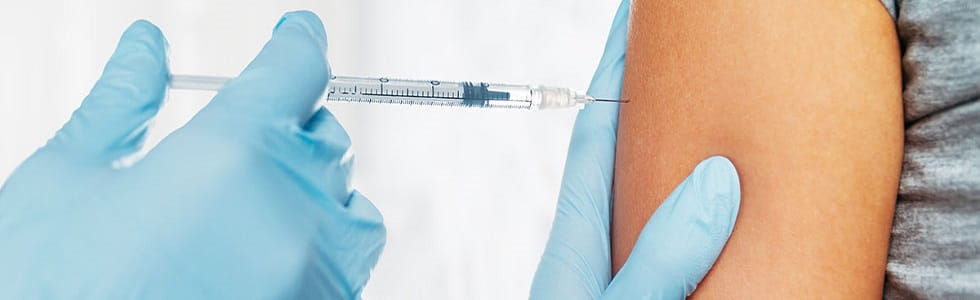 Impfung über eine Einmalkanüle Arzt spritzt Patienten eine Impfung mit einer Spritze und einer Einmalkanüle